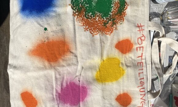 Zu sehen ist eine Stofftasche, die mit Sprühfarben bunt gestaltet wurde. 